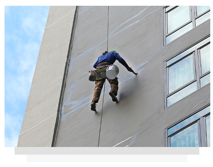 Abseiler rappelling down a tall building facade with equipment in hand
