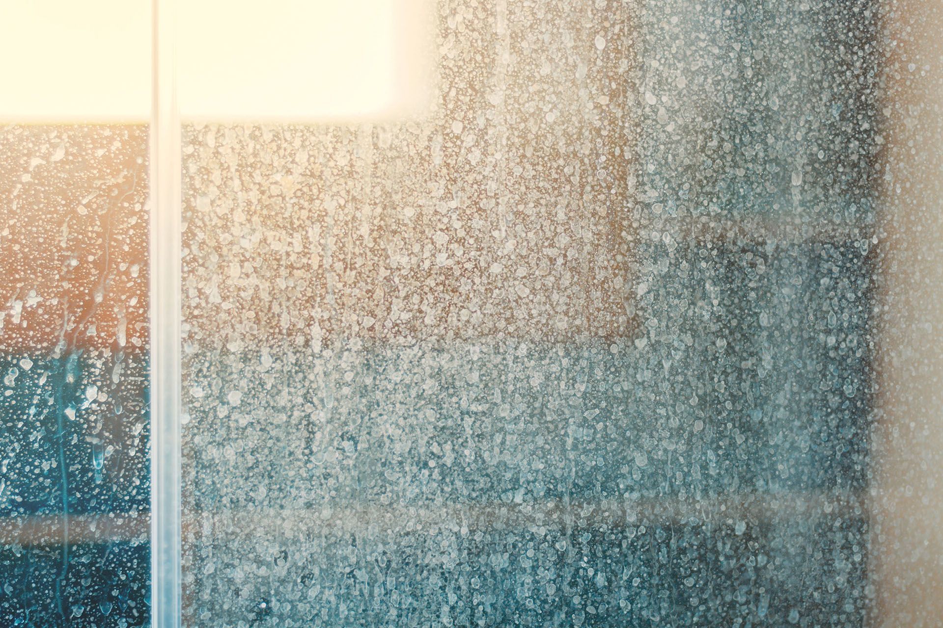 A close up of a shower door with water coming out of it.