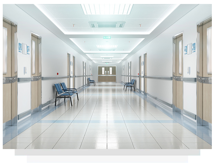 Brightly lit hospital hallway with doors, seating, and a central reception area.