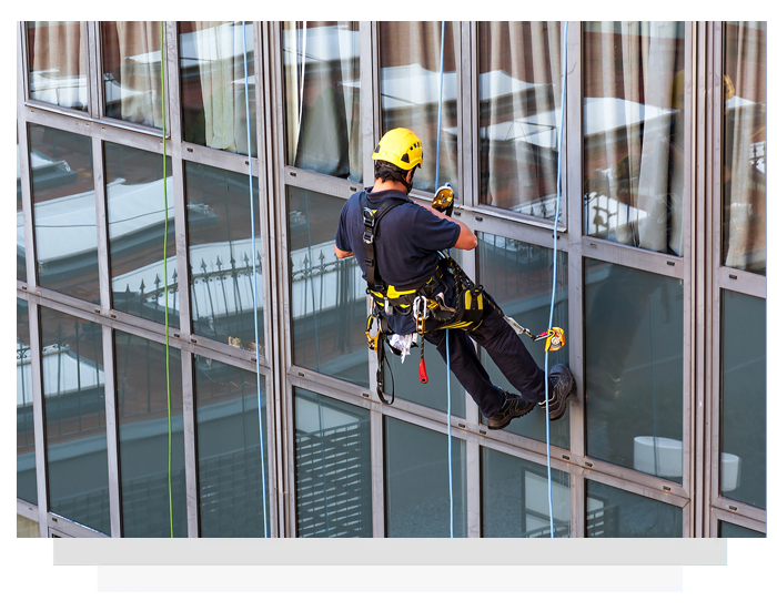 A man is cleaning the windows of a tall building.