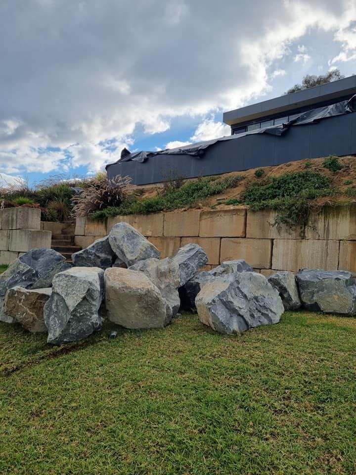 A Pile Of Rocks Sitting On Top Of A Lush Green Field — Grants Excavations In Osbornes Flat, VIC
