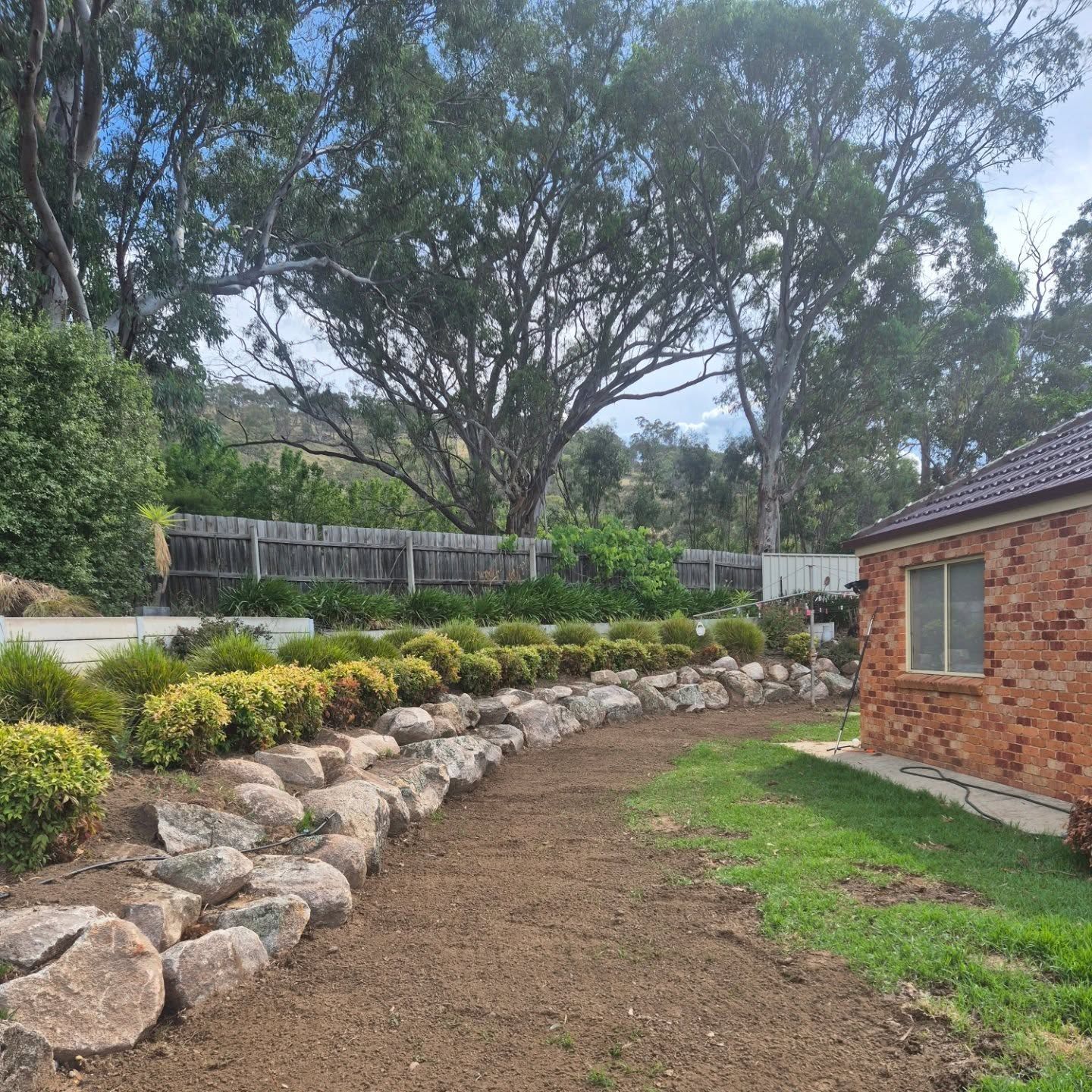 A Brick House Is Sitting On Top Of A Lush Green Hillside — Grants Excavations In Osbornes Flat, VIC
