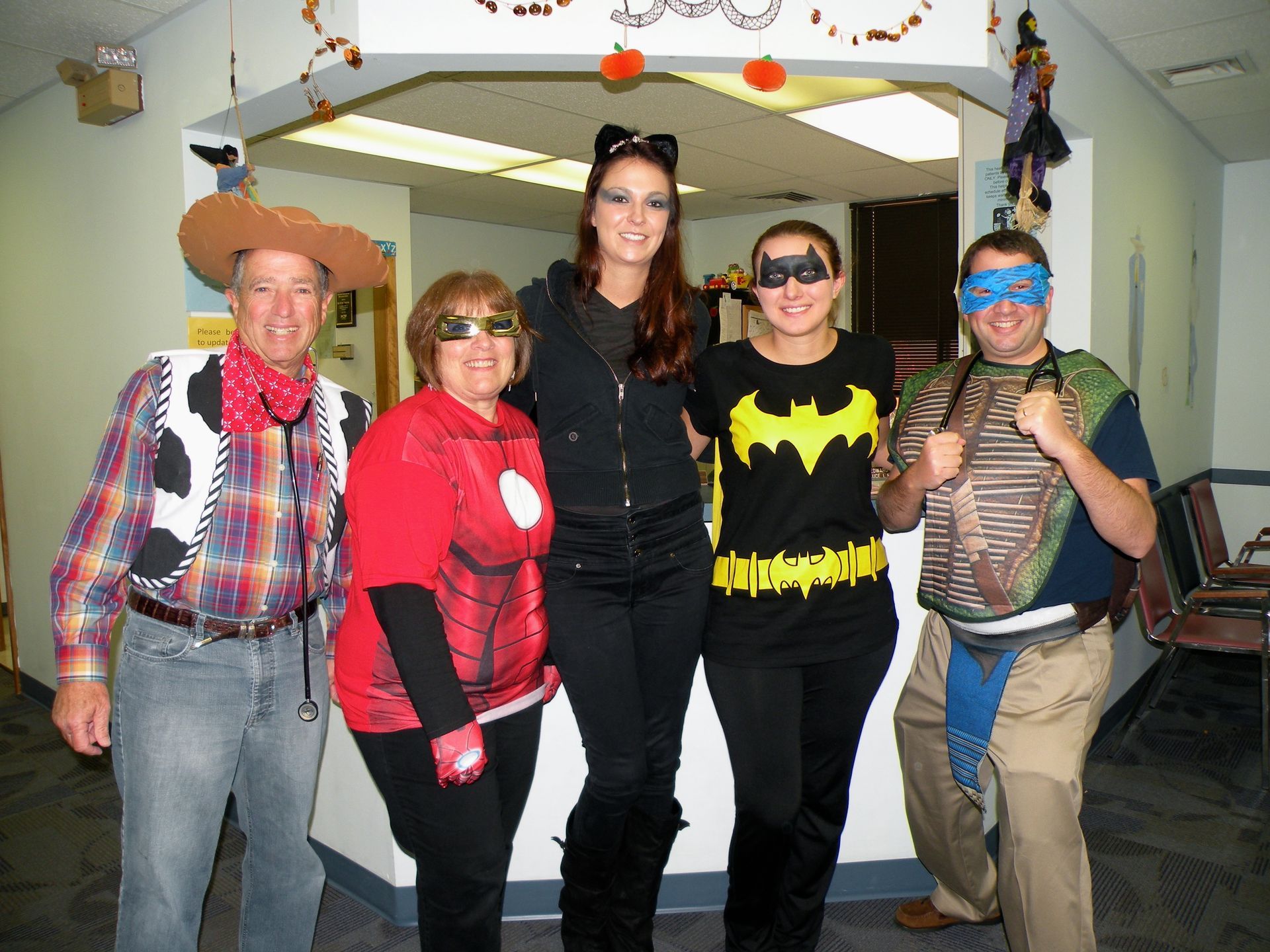 A group of people dressed in halloween costumes pose for a picture.