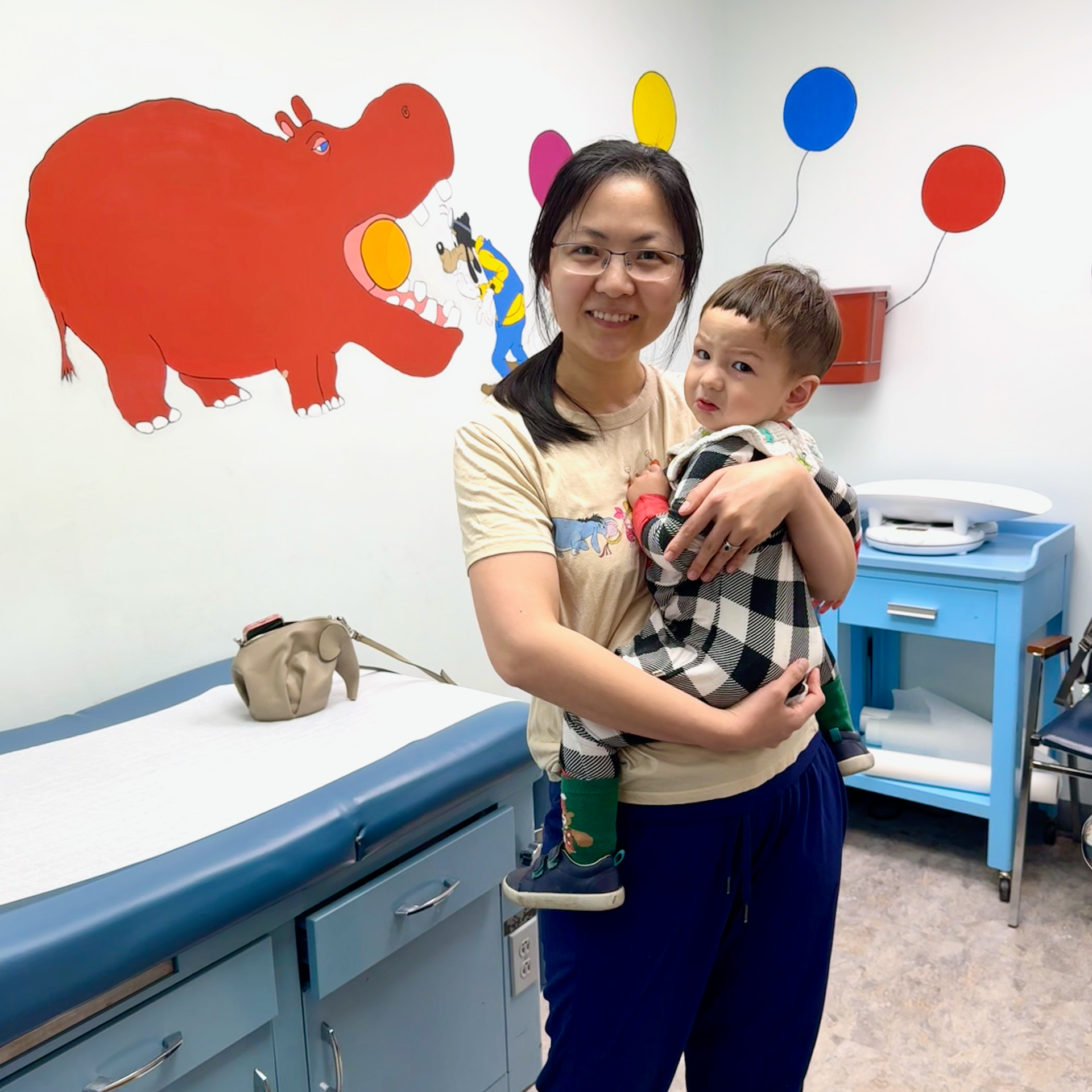 A woman is holding a baby in a doctor 's office