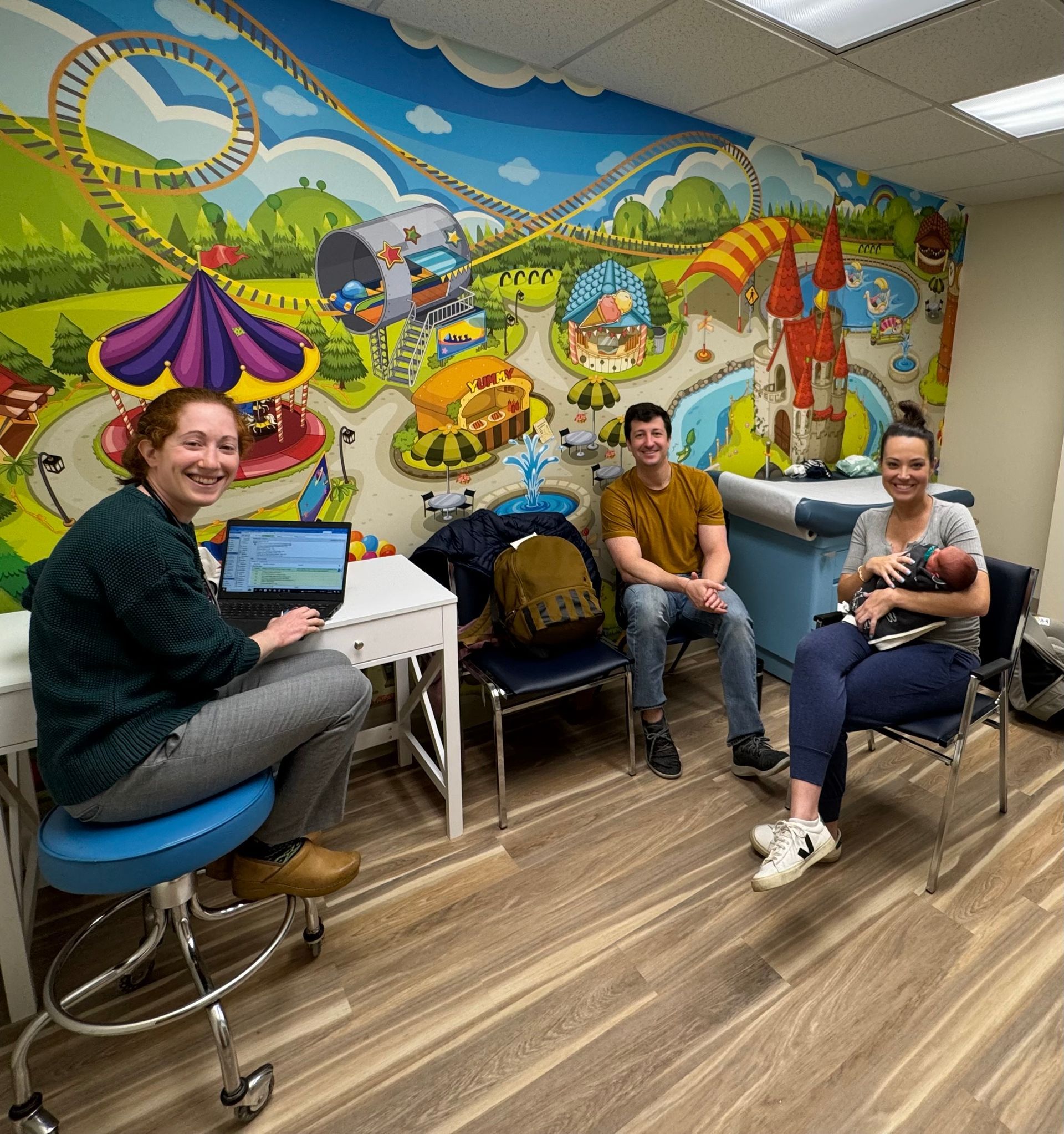 A group of people are sitting in a room with a mural on the wall.