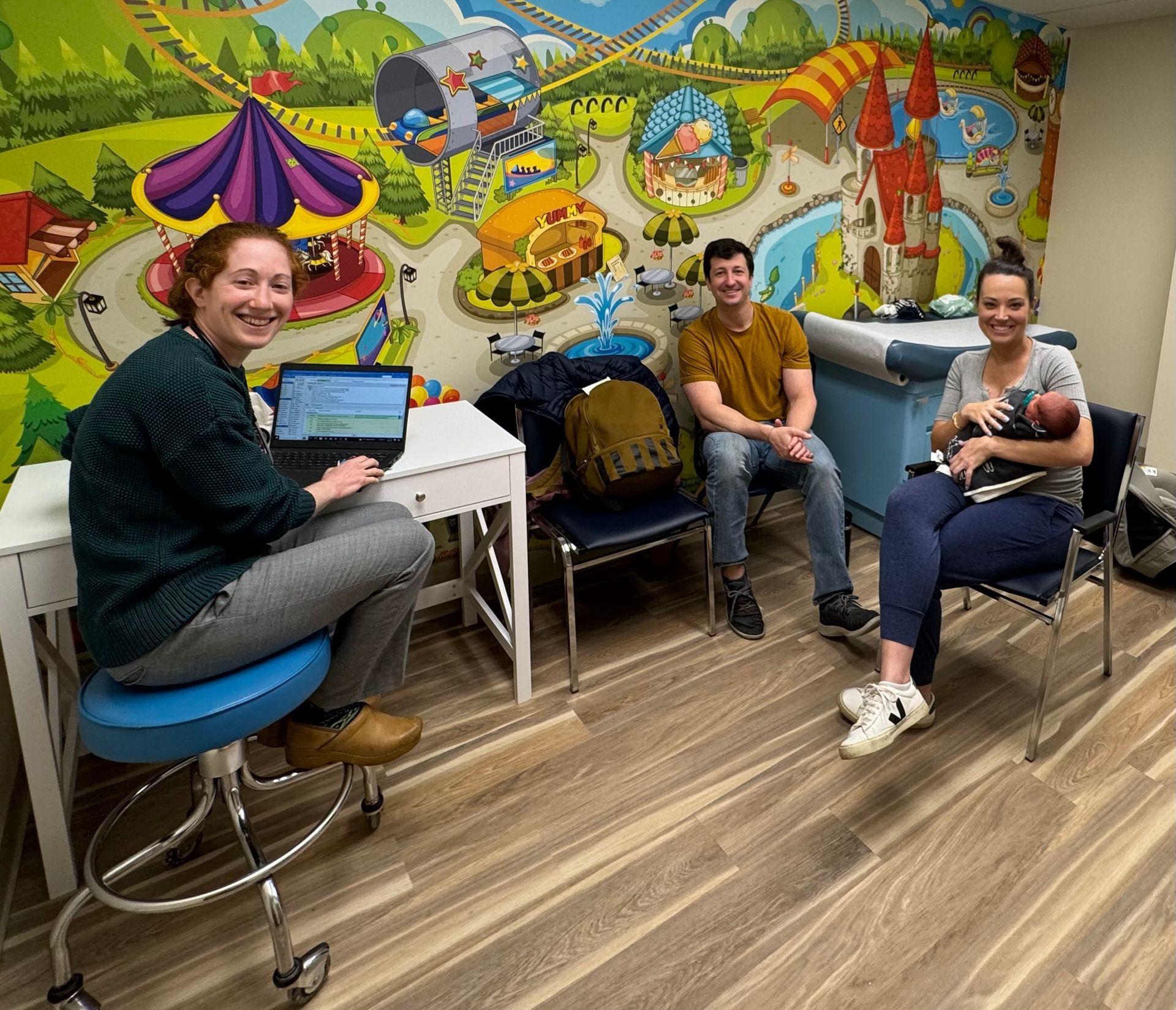 A group of people are sitting in a room with a mural on the wall.