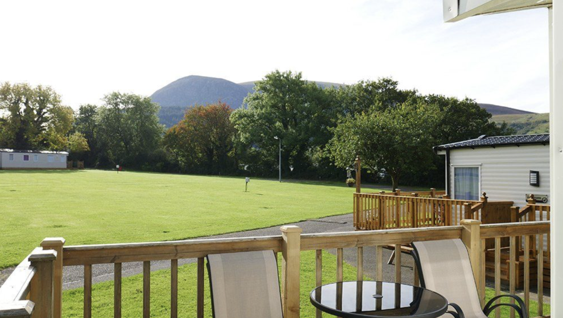a deck with a table and chairs and a view of a field