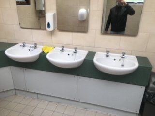 a man is taking a picture of himself in a bathroom with three sinks