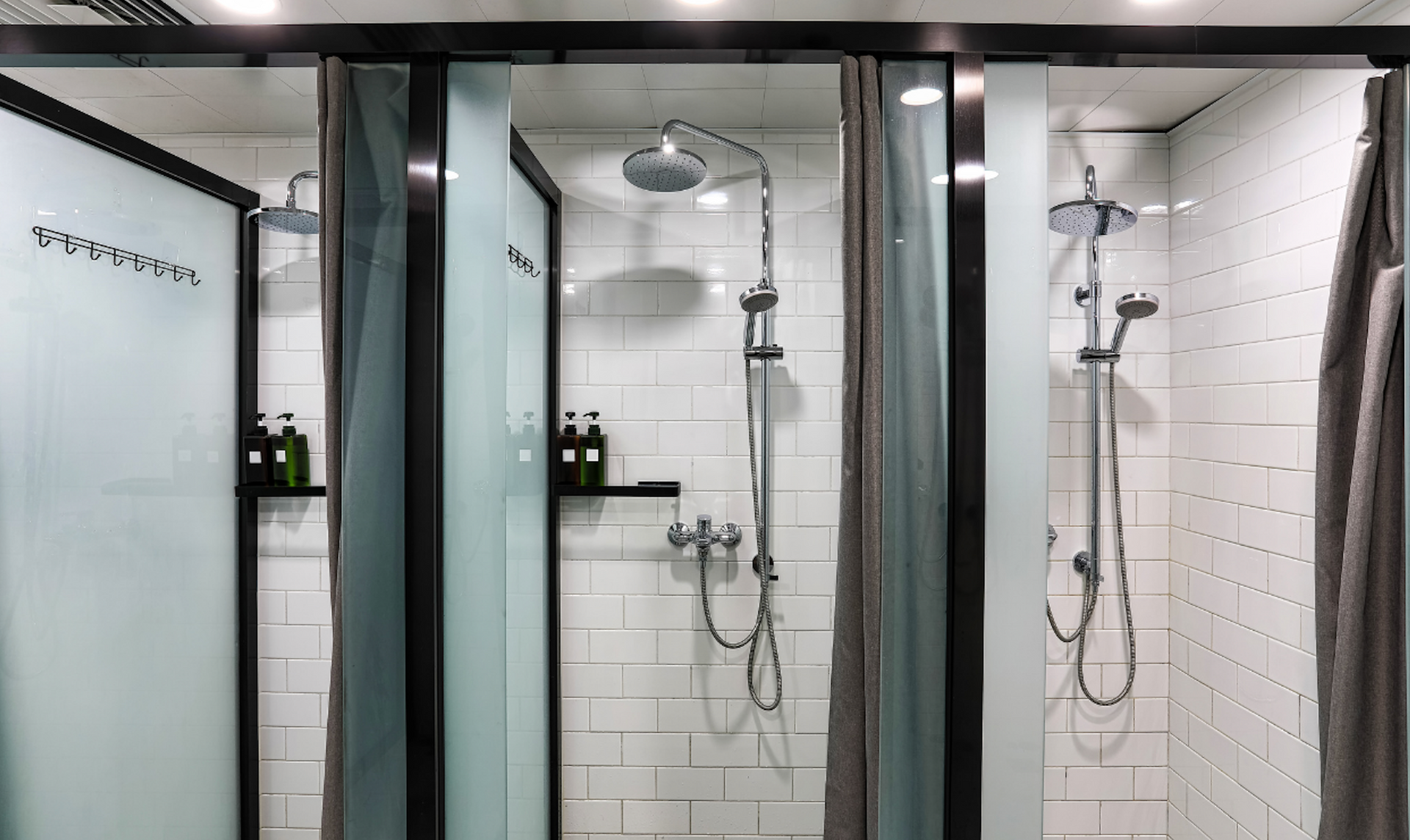 Modern bathroom shower stalls with glass doors and chrome showerheads