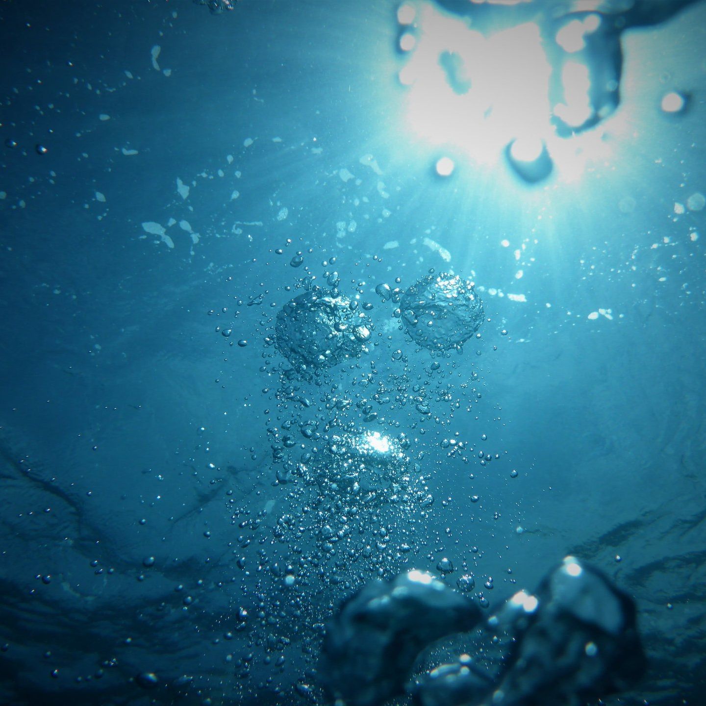 The sun is shining through the water bubbles in the ocean.