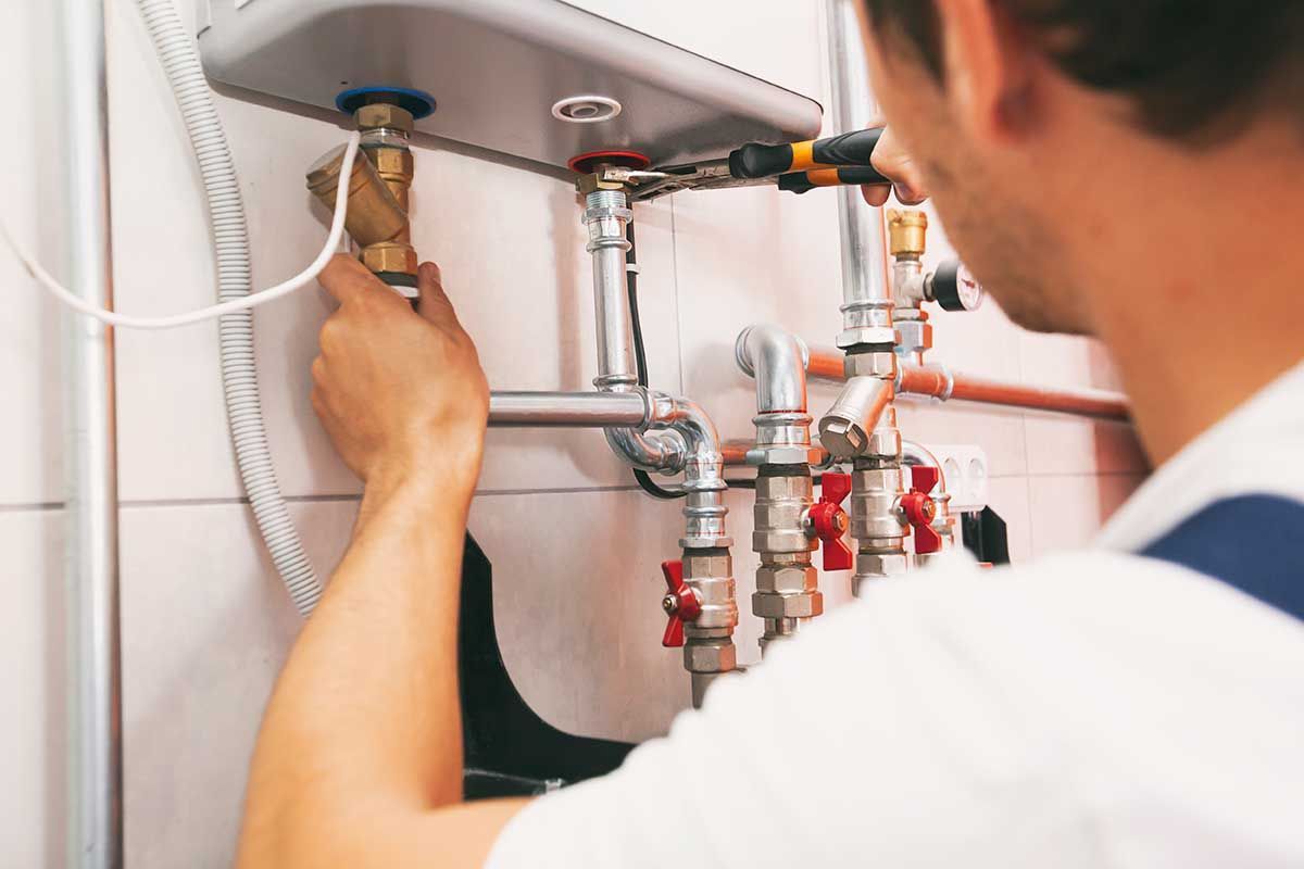 A man is fixing a water heater in a bathroom.