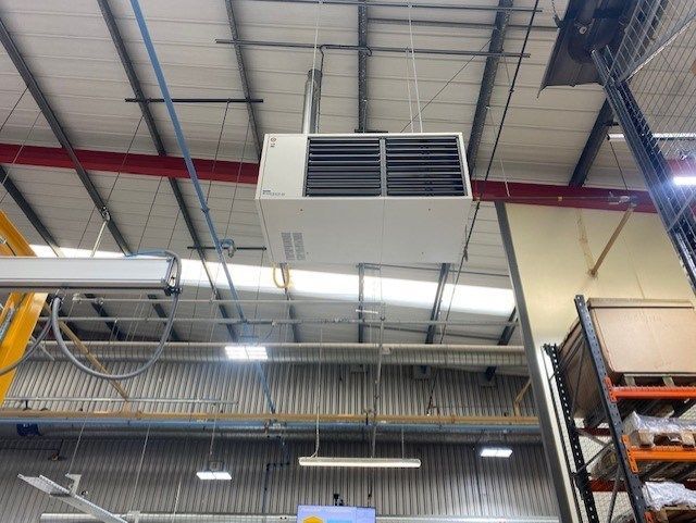a large warm air heater is hanging from the ceiling of a warehouse.