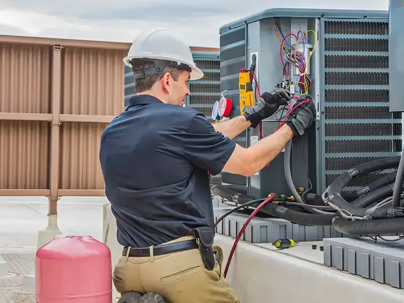 HVAC technician inspecting and servicing a commercial air conditioning unit, ensuring proper refrigerant levels and system functionality.
