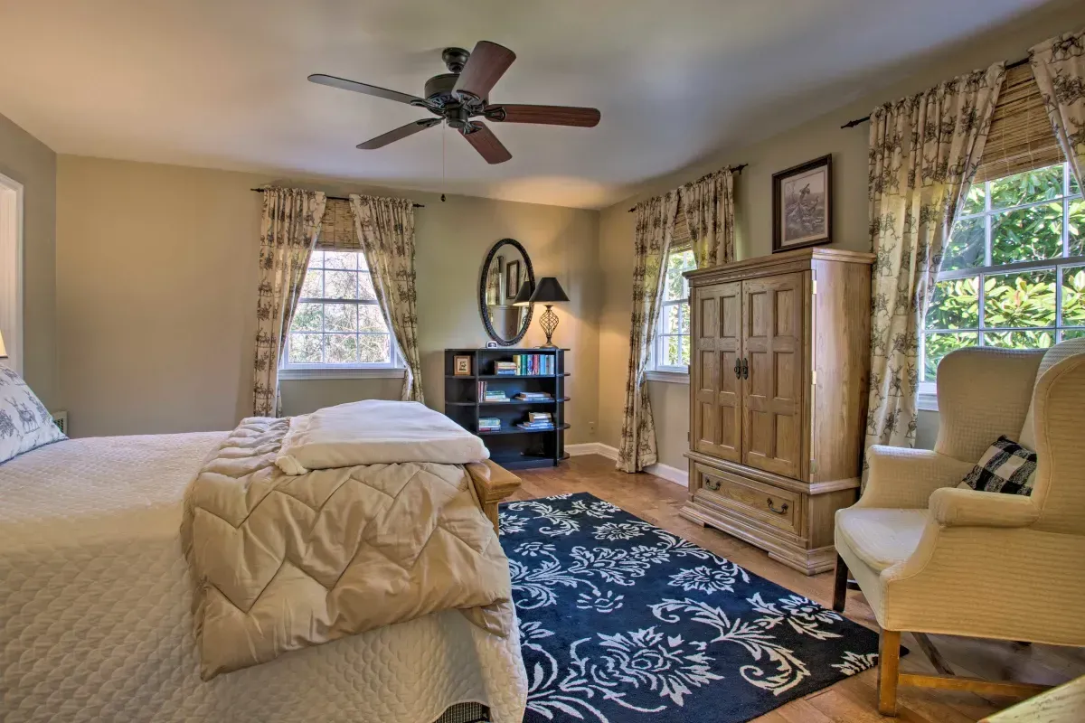 a bedroom with a bed , chair , dresser and ceiling fan .