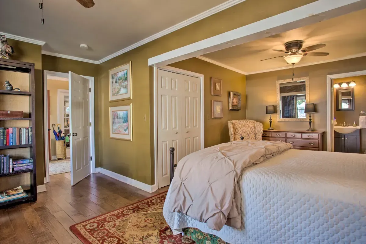 a bedroom with a bed , dresser , chair , bookshelf and ceiling fan .