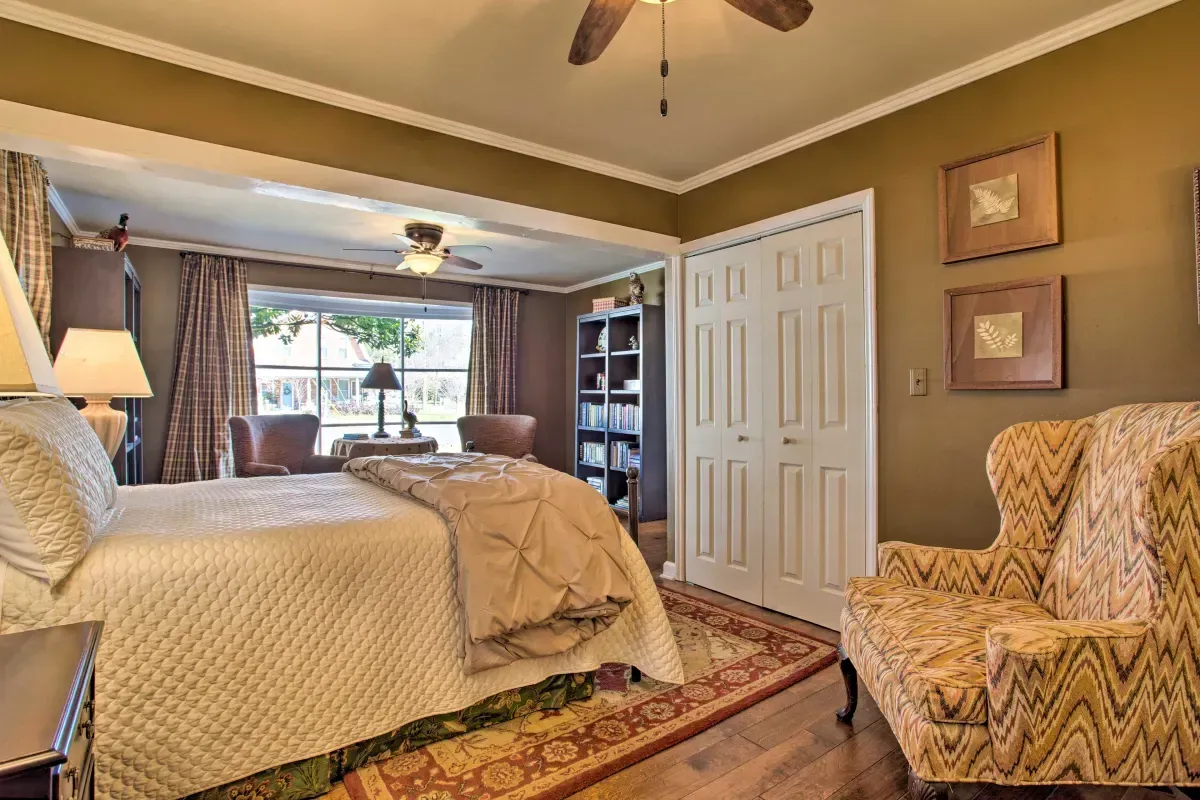 a bedroom with a bed , chairs , lamps and a ceiling fan .