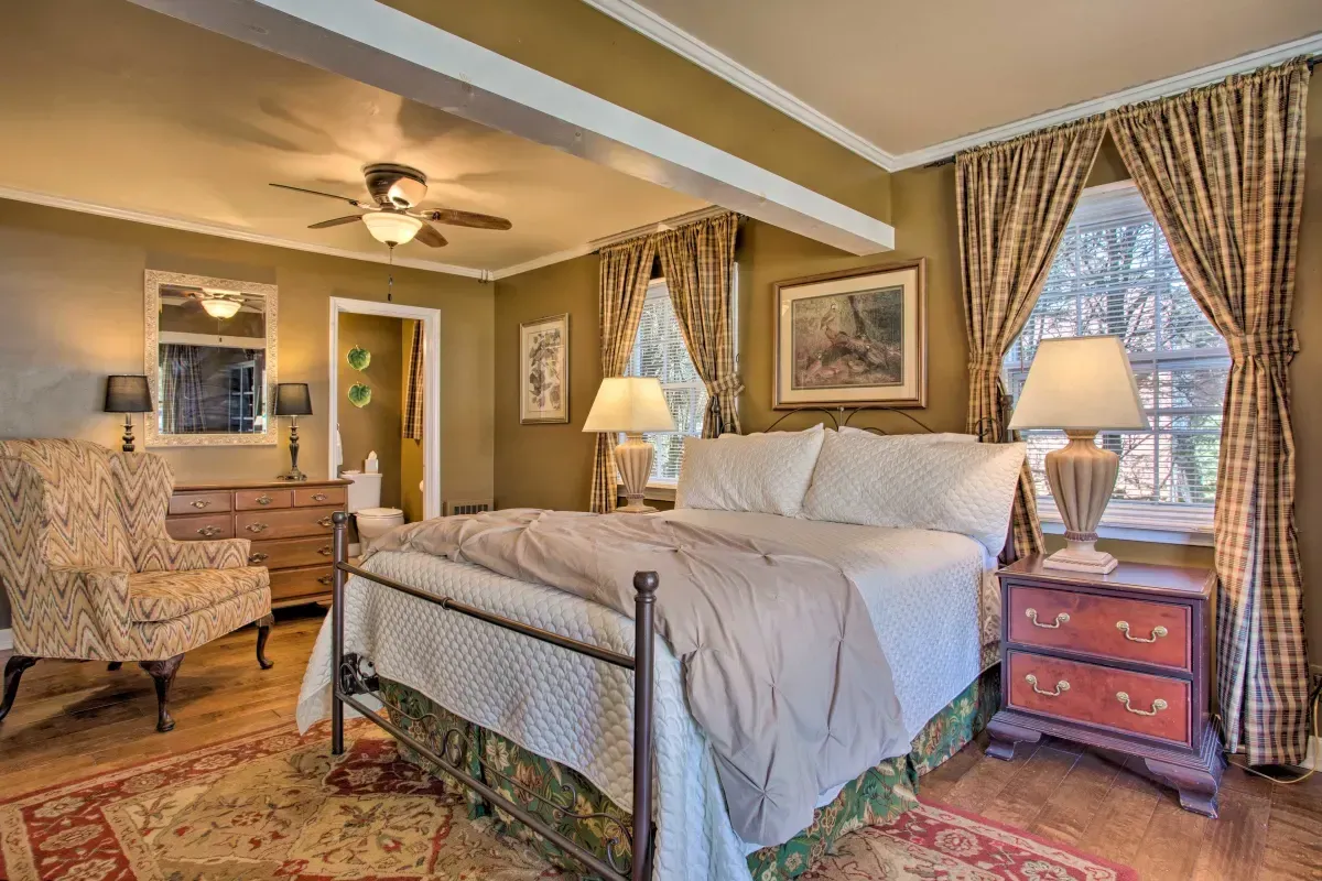 a bedroom with a bed , chair , nightstand , dresser and ceiling fan .