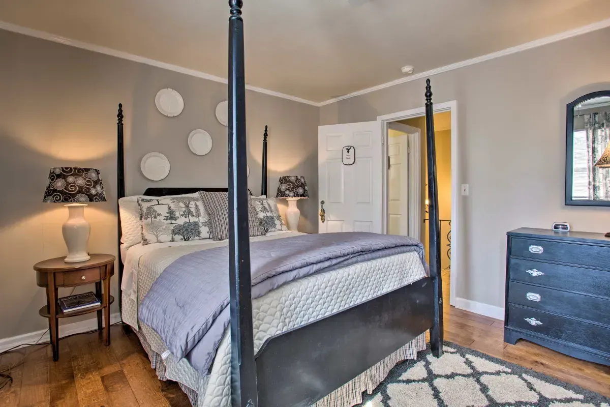a bedroom with a four poster bed , dresser , nightstand and mirror .