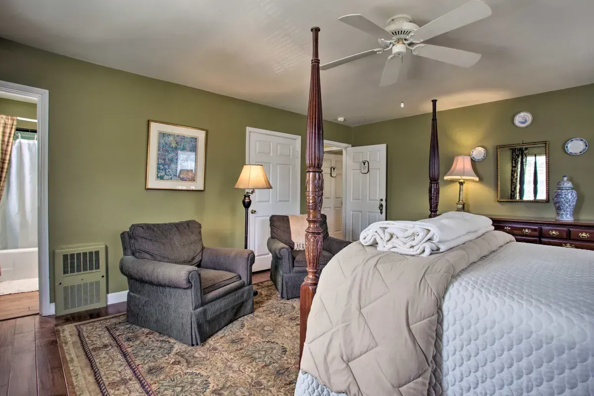 a bedroom with a four poster bed , chairs and a ceiling fan .