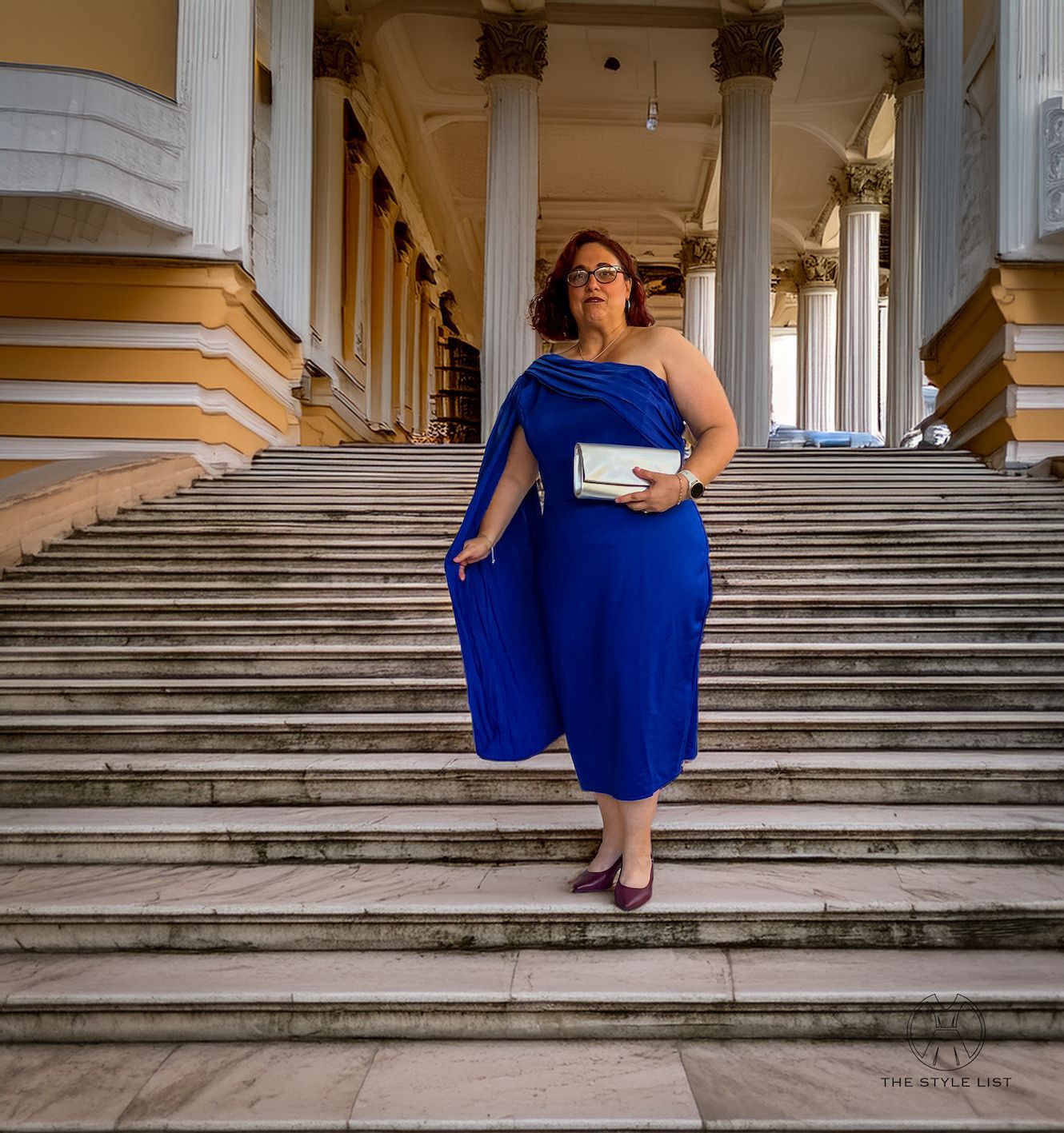 A woman in a blue dress is standing on a set of stairs