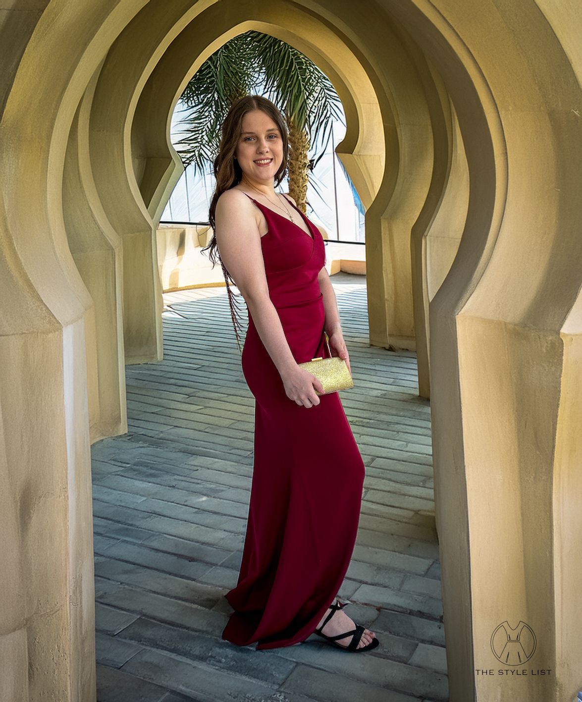 A woman in a red dress is standing in an archway