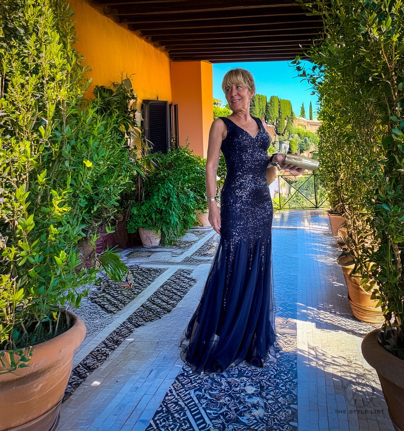 A woman in a long blue dress is standing on a patio