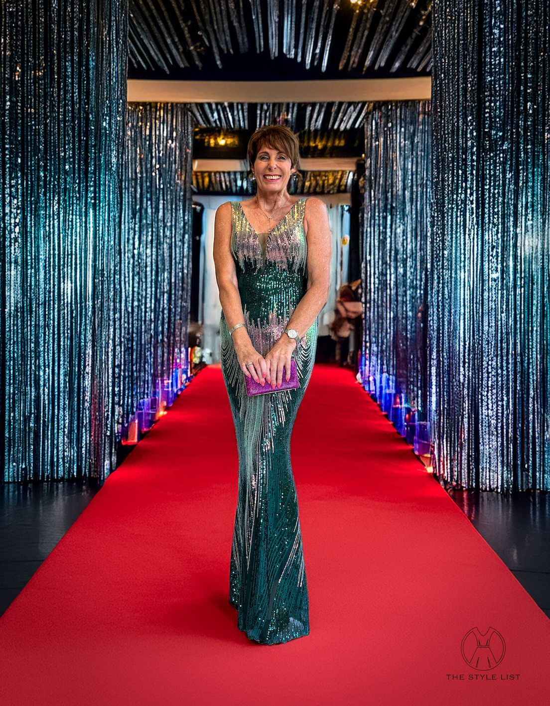 A woman in a green dress is standing on a red carpet.