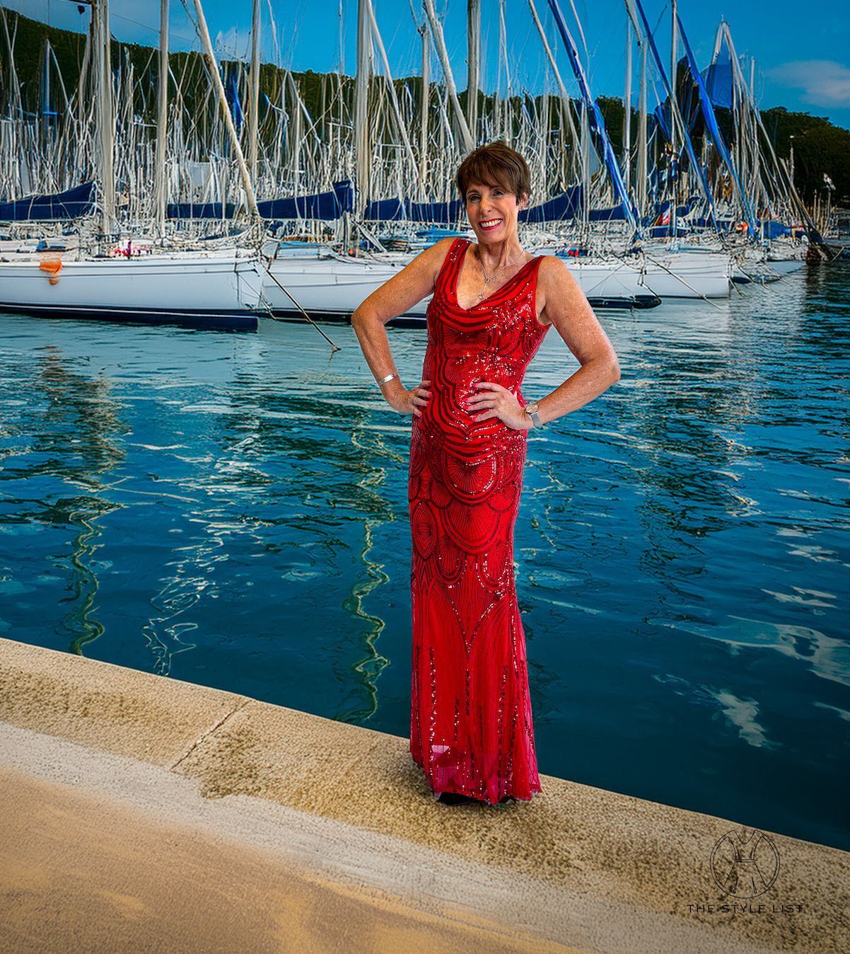 A woman in a red dress is standing next to a body of water