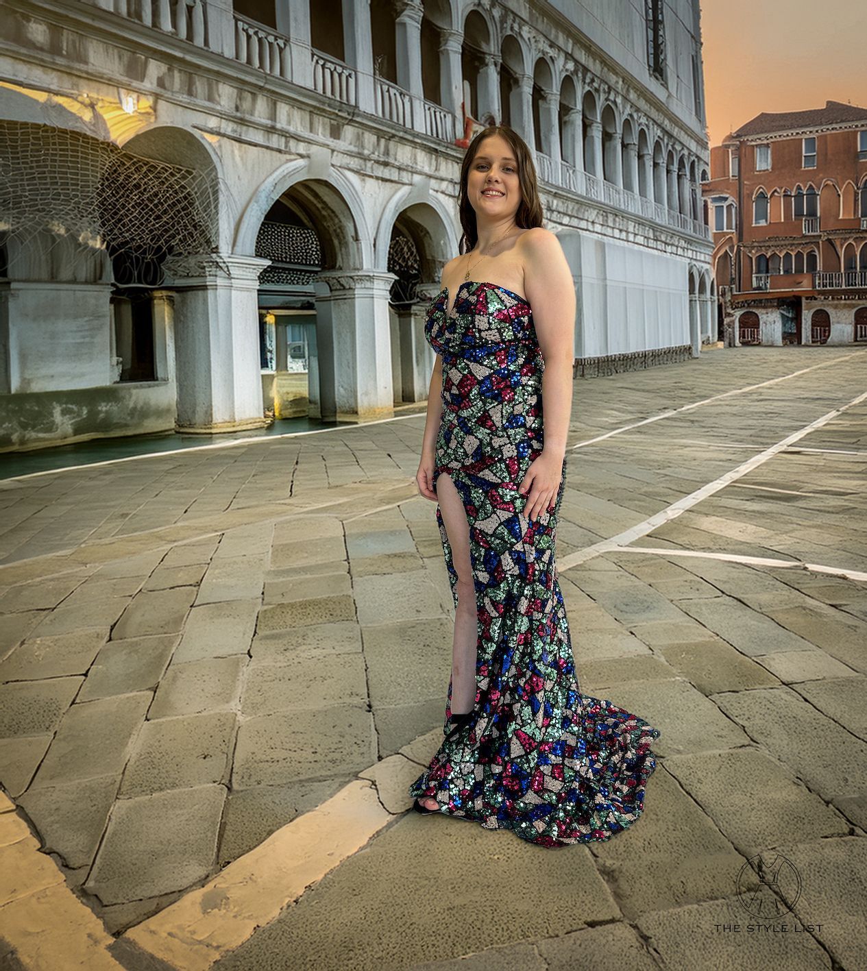 A woman in a strapless dress is standing in front of a building.