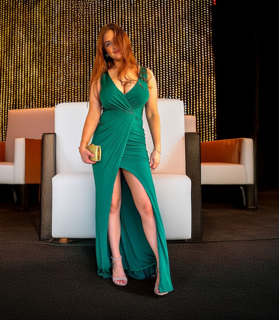 A woman in a green dress is standing next to a chair