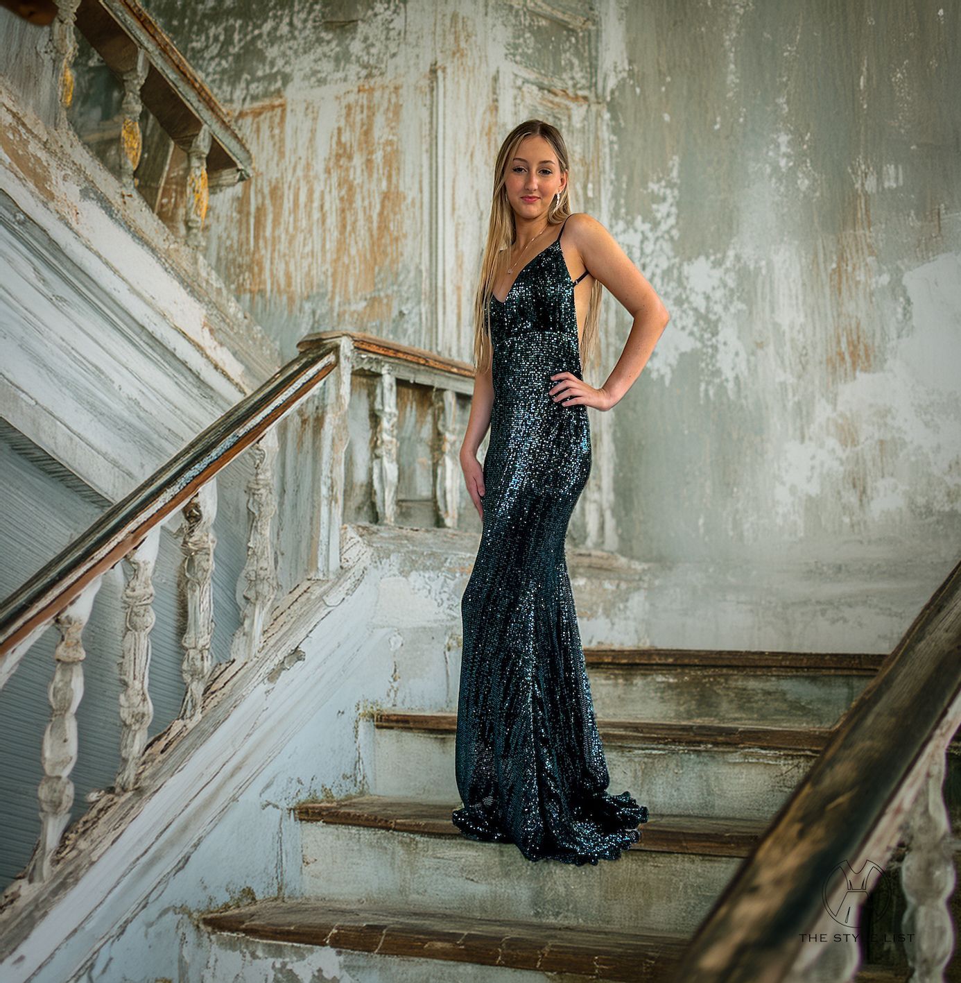 A woman in a long black dress is standing on a set of stairs