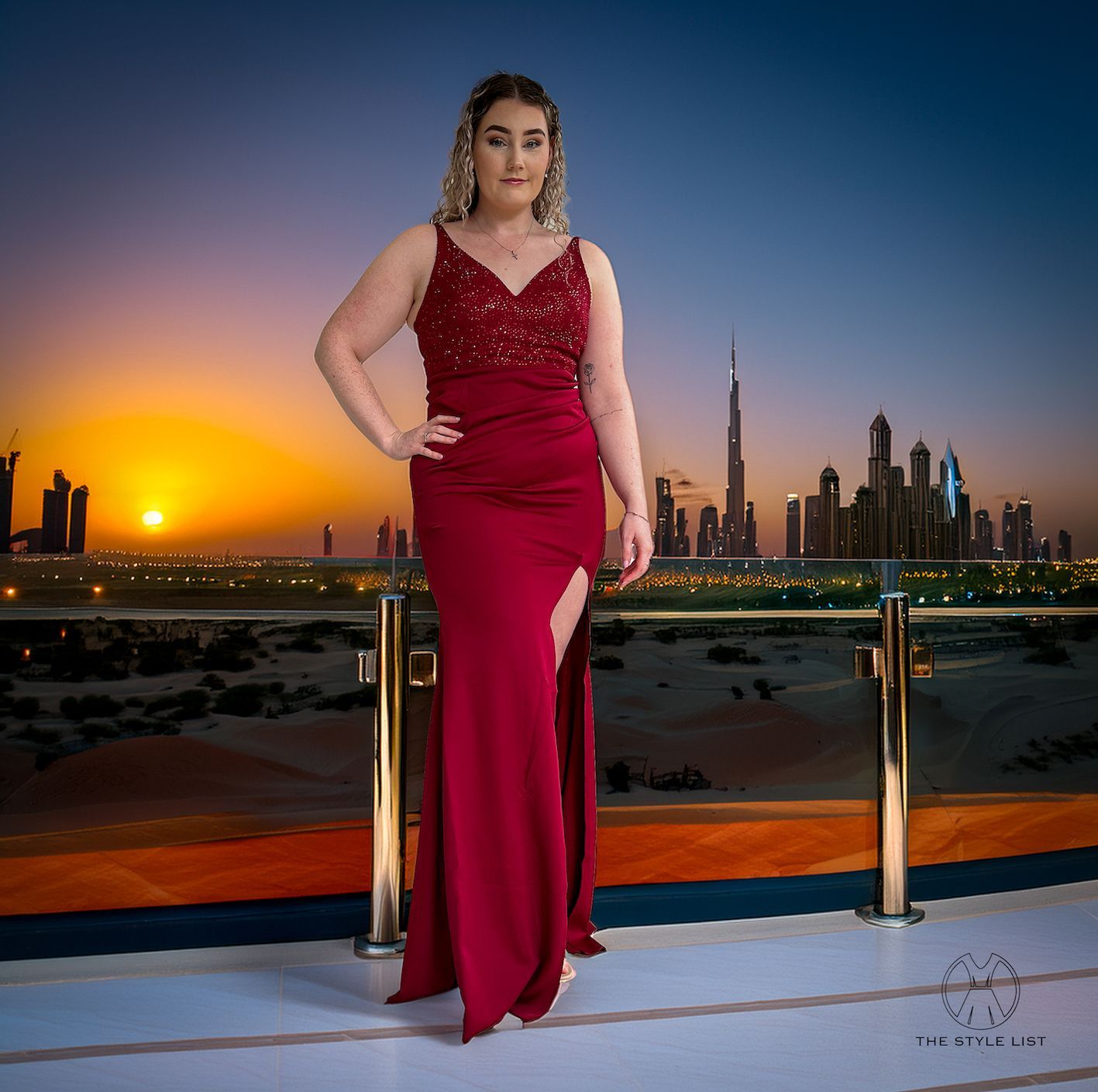 A woman in a red dress is standing on a balcony overlooking a city.