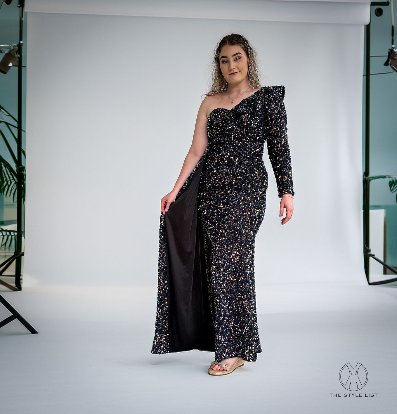 A woman is wearing a black one shoulder dress