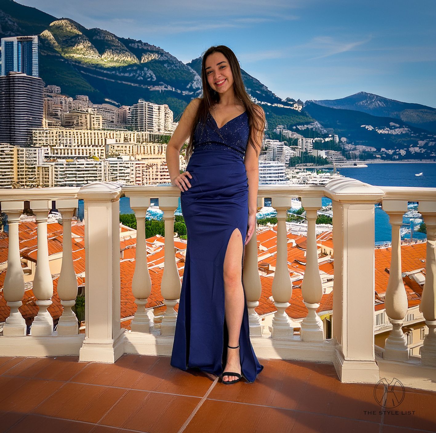 A woman in a blue dress is standing on a balcony overlooking a city