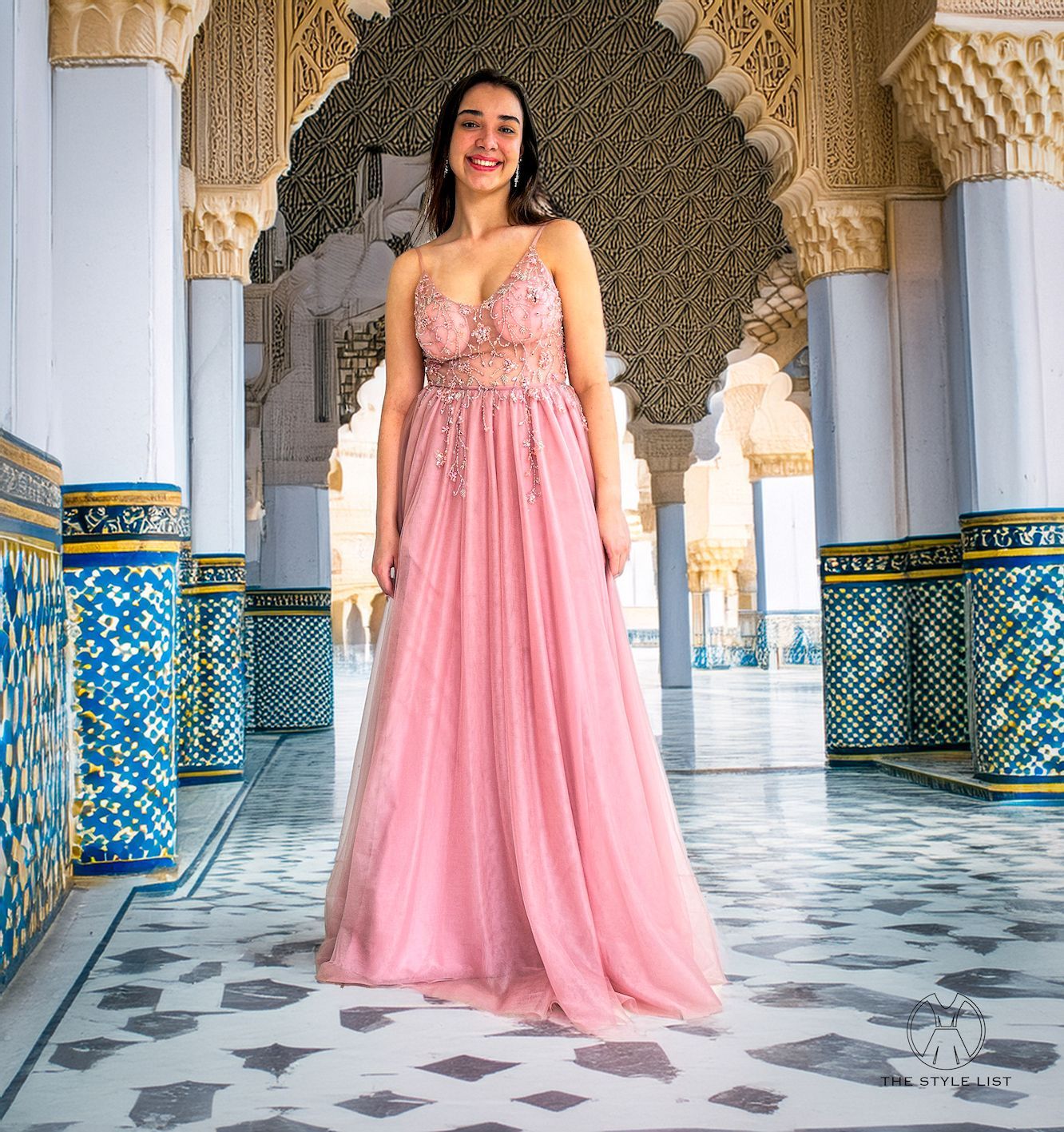 A woman in a pink dress is standing in a hallway.
