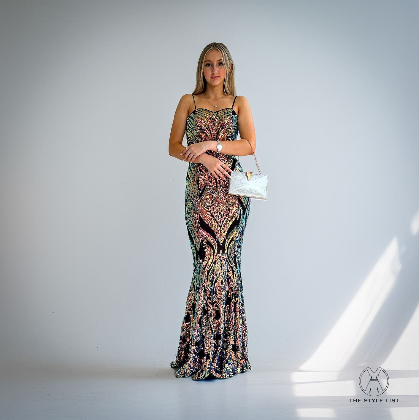 A woman in a long dress is holding a white purse