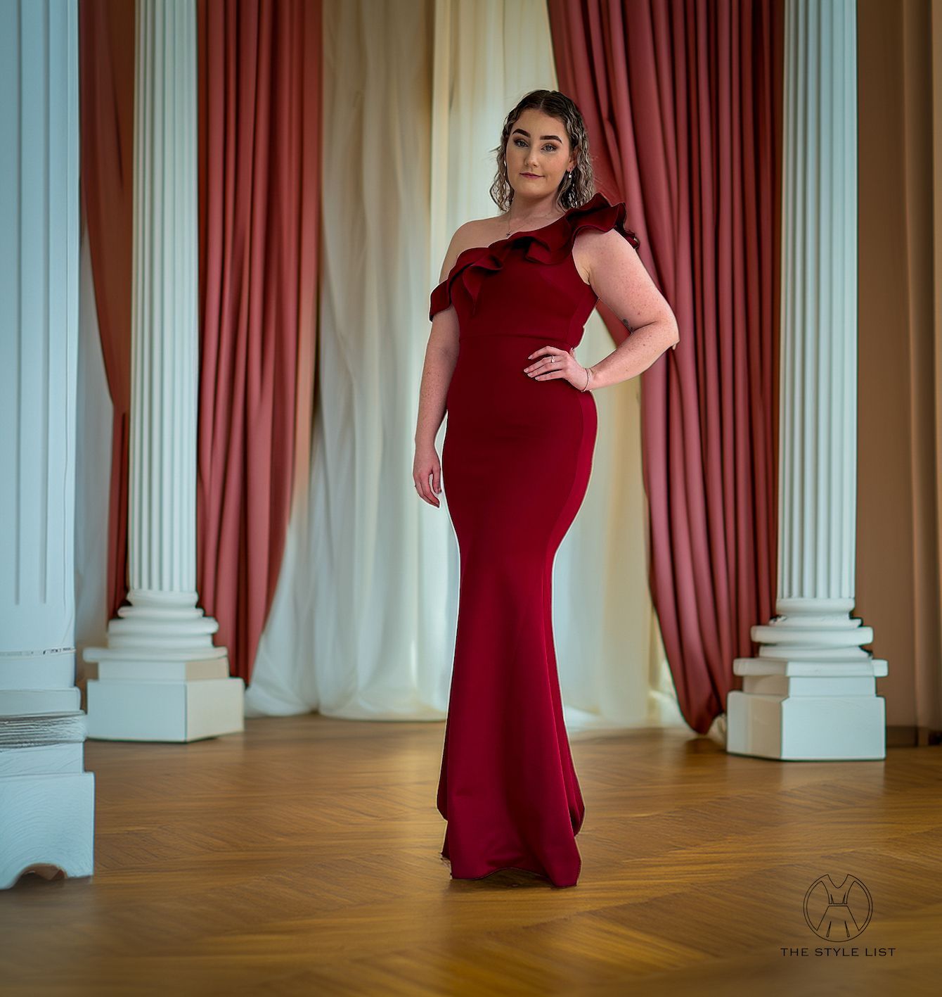 A woman in a red dress is standing in front of columns