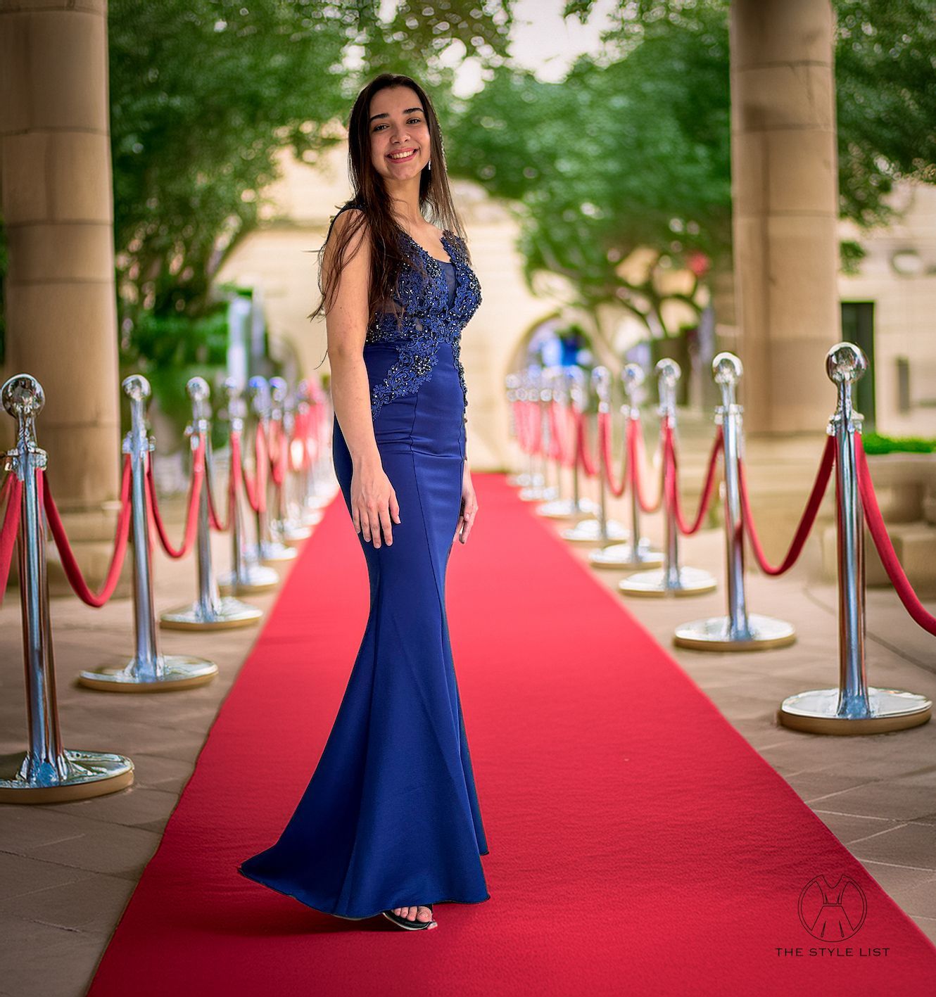 A woman in a blue dress is standing on a red carpet