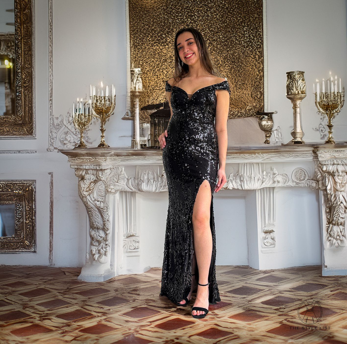 A woman in a black dress is standing in front of a fireplace