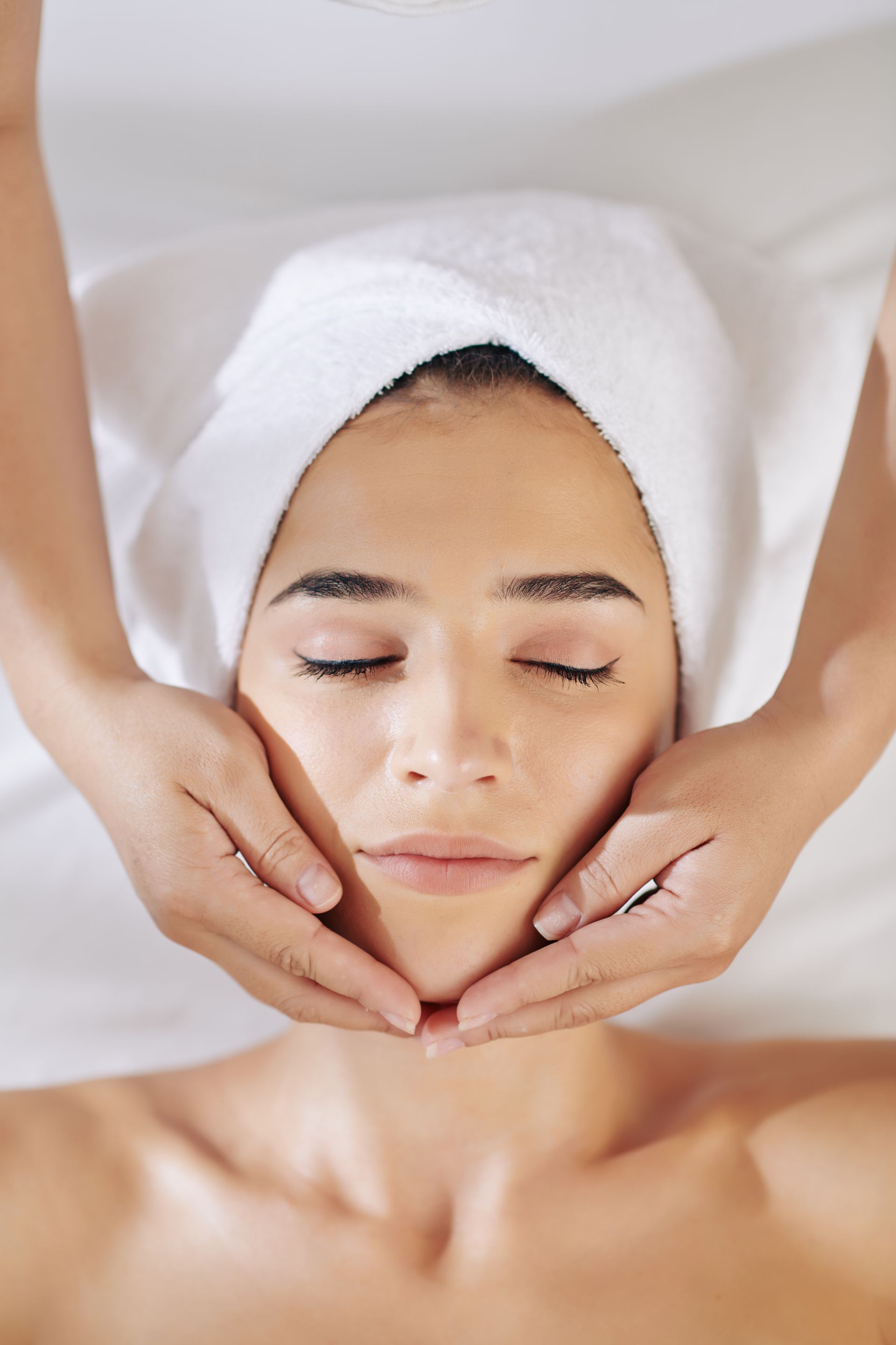 a woman with a towel wrapped around her head is getting a facial massage
