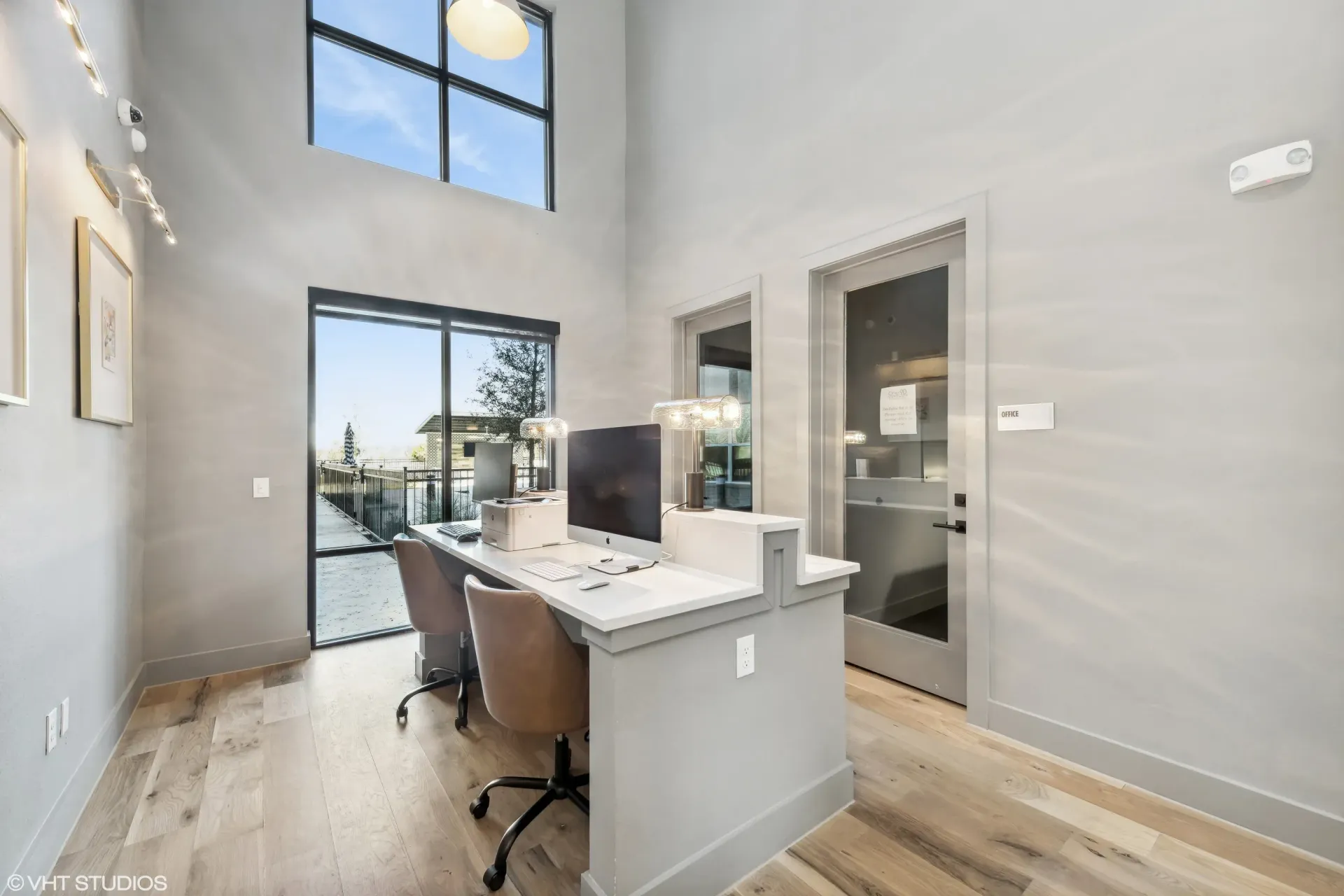 Leasing office with a long desk, two chairs, computer, and large windows.