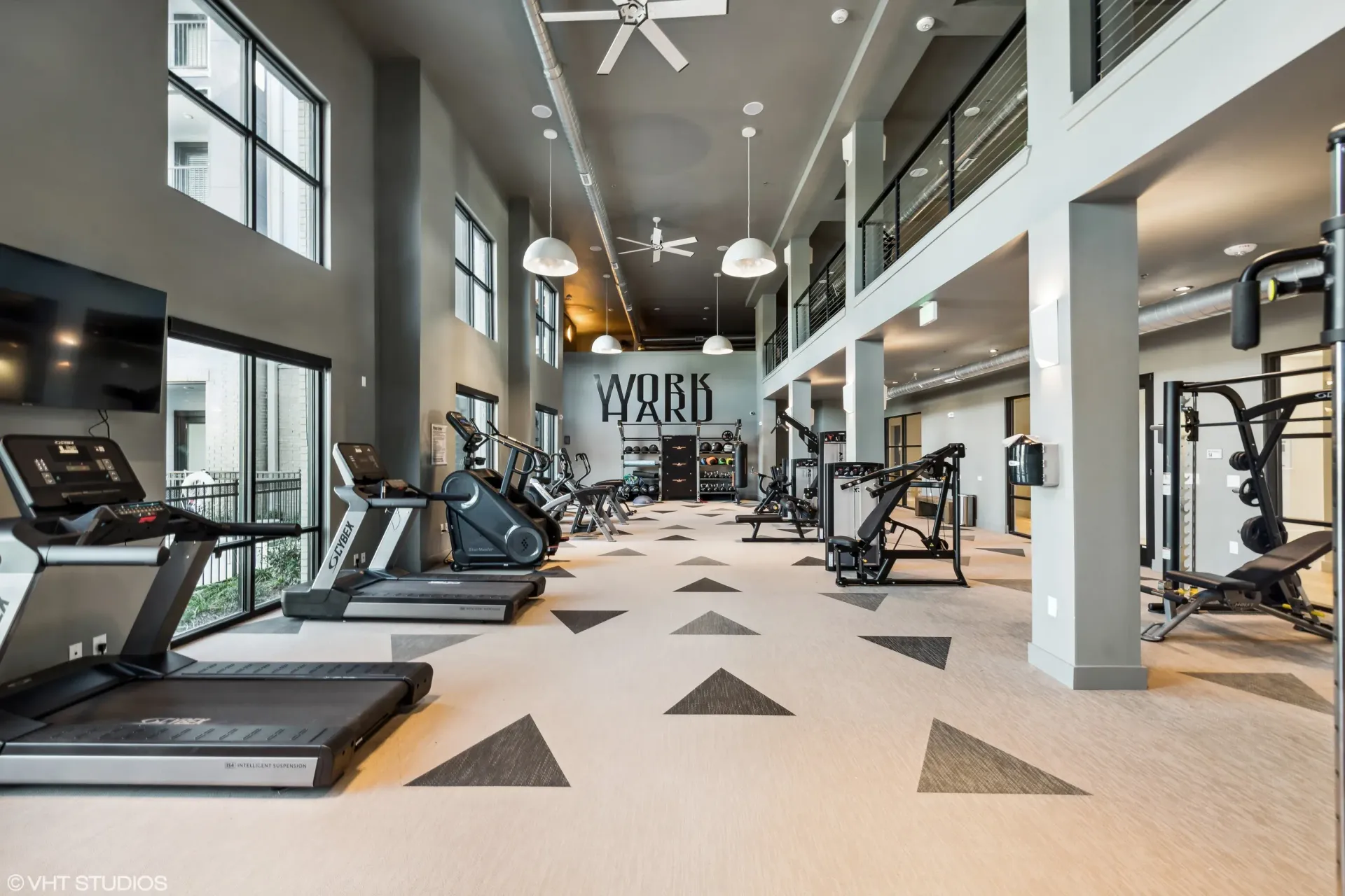 Interior of a modern apartment community gym with treadmills and weight machines.