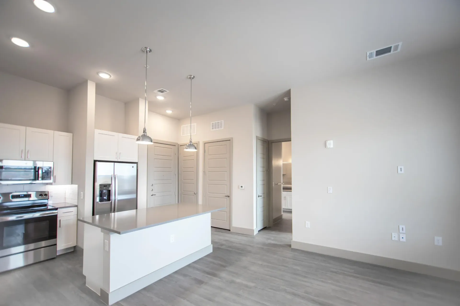 Bright modern kitchen with white cabinets, stainless steel appliances, and an island.