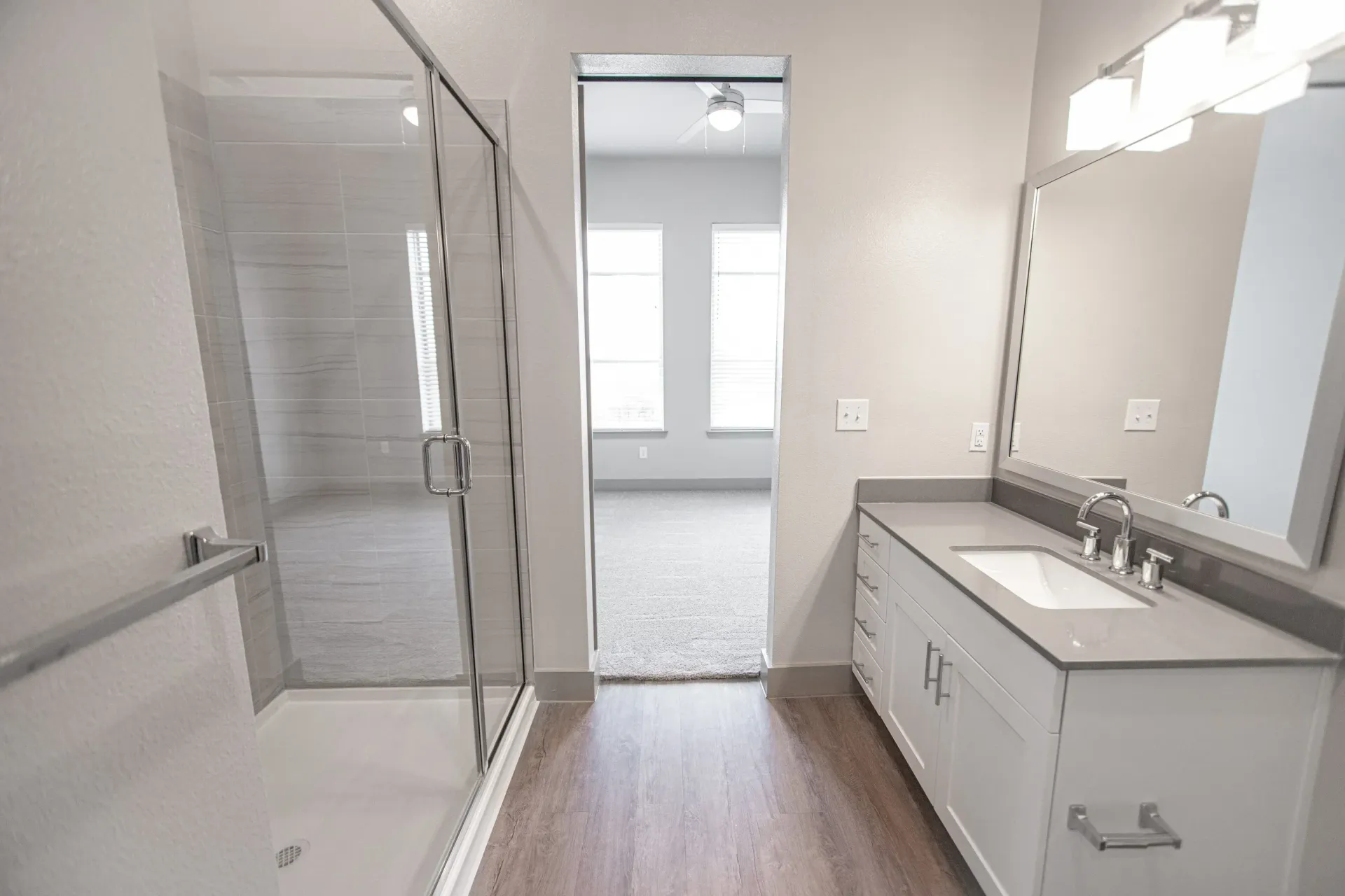 Bathroom with glass-enclosed shower, white vanity, and gray countertop.
