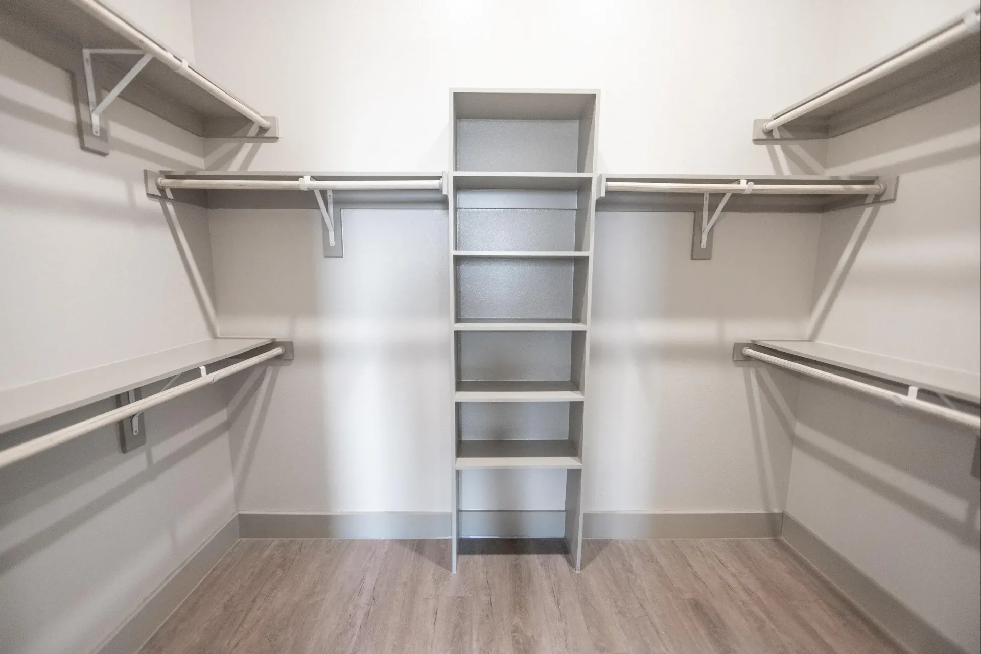 Walk-in closet with center shelving unit and double-sided hanging rods.