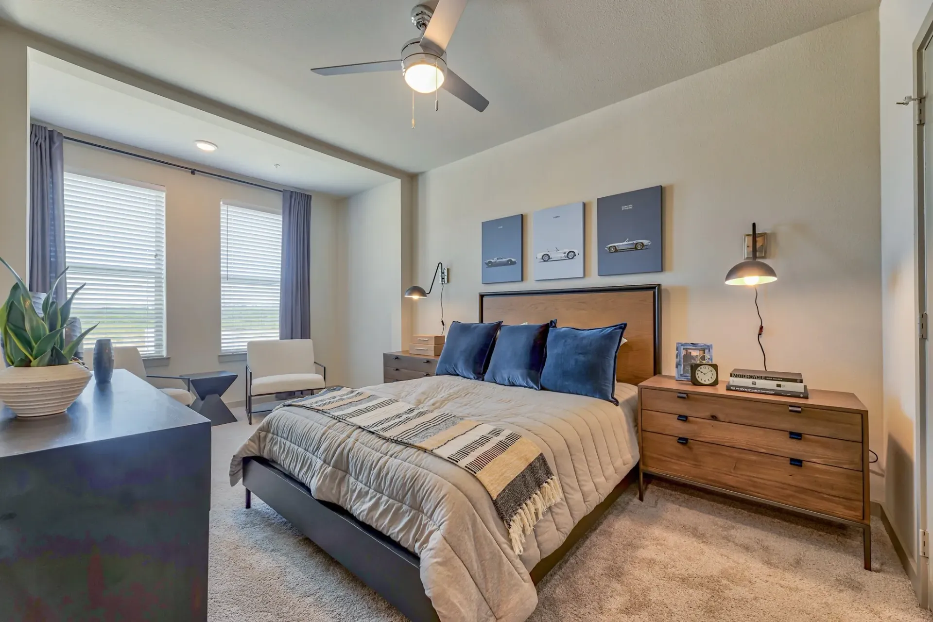Bedroom with a wooden headboard, a bed, two nightstands, ceiling fan, and two windows with blinds.
