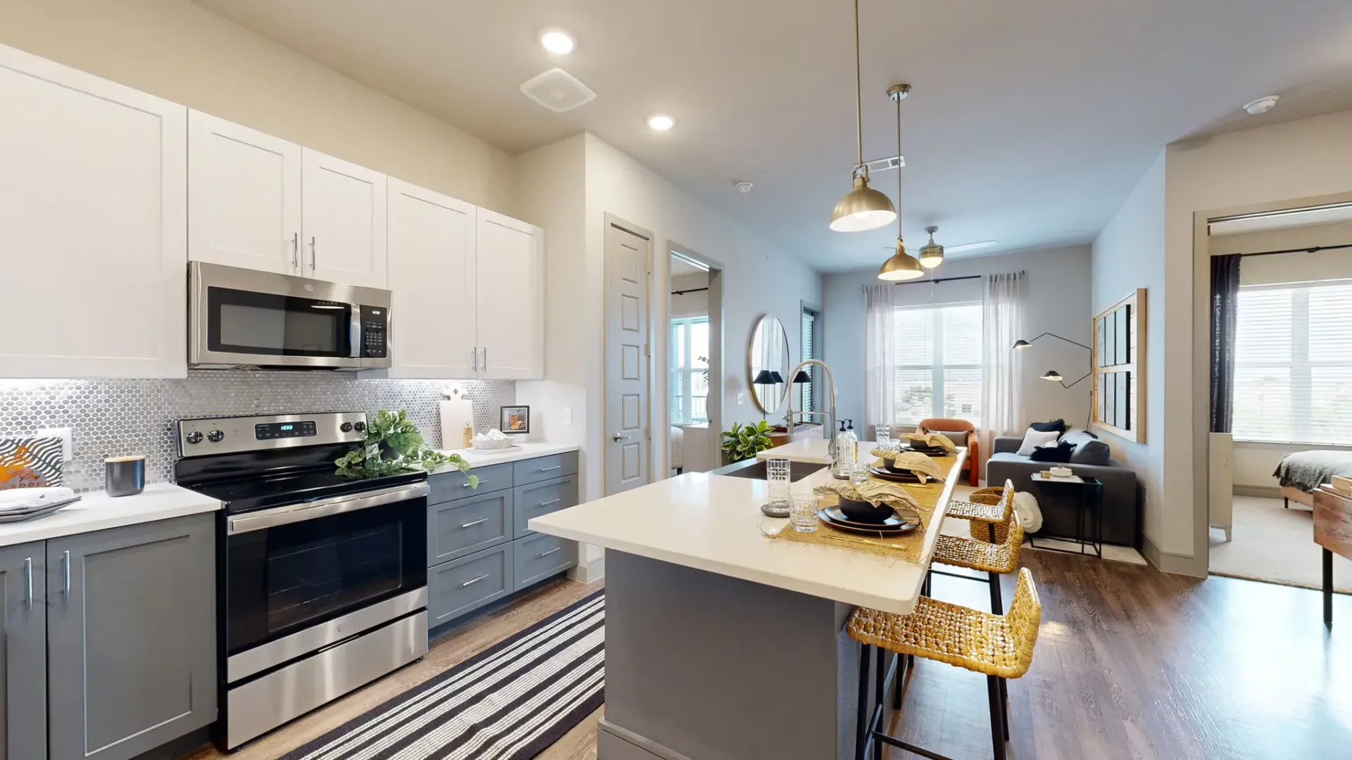 Open-concept kitchen with white upper cabinets, gray lower cabinets, stainless steel appliances, and an island.