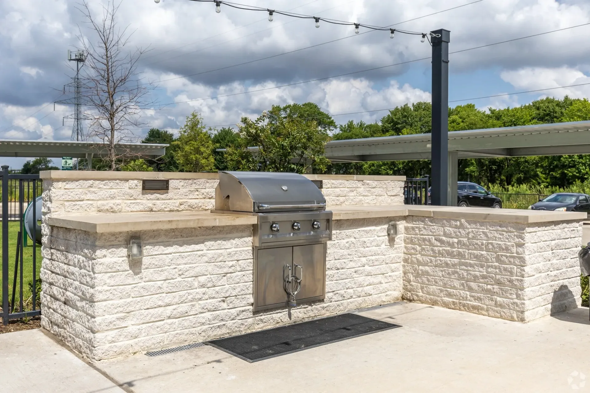 Outdoor community grilling station with a stainless steel grill set in a light stone counter.