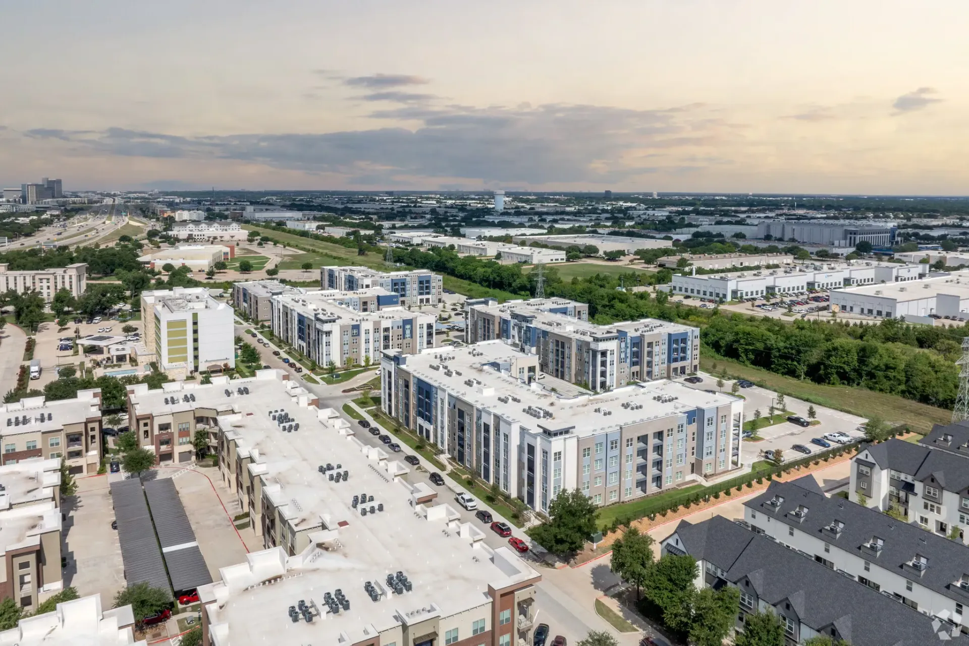 Aerial view of a modern apartment complex with multiple buildings and parking lots.