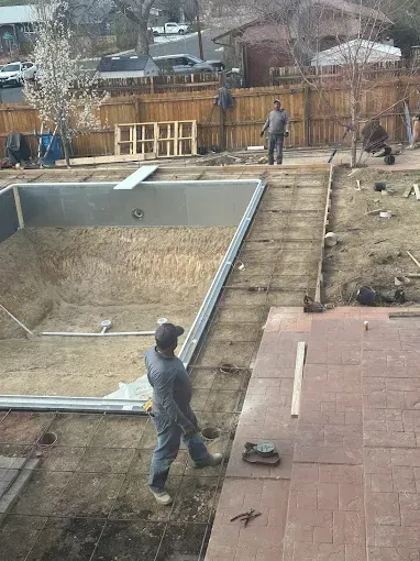 A man is standing in front of a swimming pool under construction.